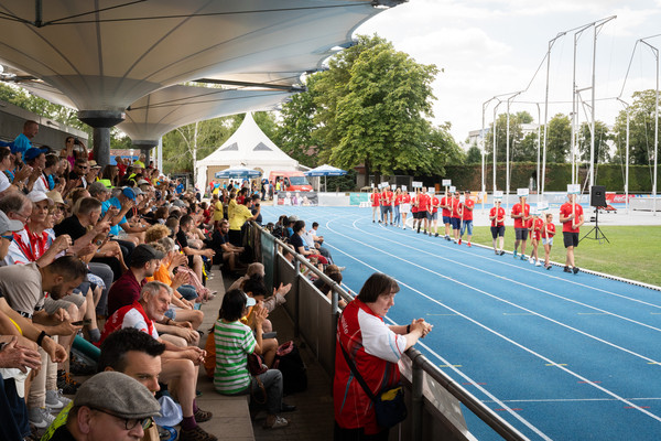 Man sieht ein Stadion und Sportlerinnen und Sportler die Schilder in die Höhe halten.