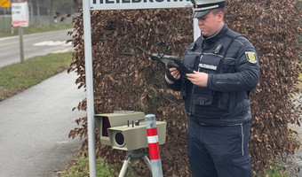 Auf dem Bild ist ein Mitarbeiter der Stadt mit einem mobilen Tempo-Messgerät am Straßenrand zu sehen.