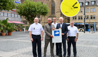 Start für die Videoüberwachung auf dem Heilbronner Marktplatz: (v.l.) Polizeipräsident Frank Spitzmüller, Innenminister Thomas Strobl, stv. Polizeipräsident Markus Geistler, Oberbürgermeister Harry Mergel und Polizeipressesprecher Frank Belz präsentieren ein Hinweisschild mit Informationen zur Videoüberwachung. Sieben davon sind rund um den Marktplatz für alle gut sichtbar angebracht. Foto: Stadtarchiv / Barbara Kimmerle