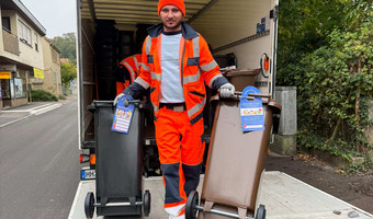 Das Bild zeigt einen Mitarbeiter einer Entsorgungsfirma, der die neuen Restmüll- und Biotonnen mit integriertem Chip ausliefert.