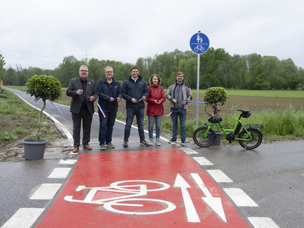Das Bild zeigt den Startpunkt des neuen Radweges bei Biberach. Bürgermeister Andreas Ringle und weitere Projektebeteiligte schneiden das Band durch und geben den Radweg frei.