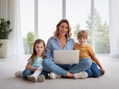 Man sieht eine Frau mit zwei Kindern und einem Laptop, die sich etwas anschauen. /KI generiertes Bild