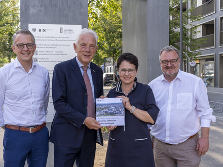 Das Bild zeigt die Übergabe der Holzbau-Broschüre zum Neckarbogen an Ministerin Marion Gentges. Mit dabei (v. li.): Stadtsiedlung-Geschäftsführer Dominik Buchta, Oberbürgermeister Harry Mergel, Baubürgermeister Andreas Ringle.