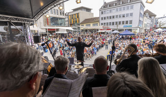 Das Bild zeigt einen Chor mit Orchester auf der Bühne am gut gefüllten Kiliansplatz bei Magie der Stimmen.