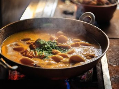 Man sieht einen Kochtopf mit einem Gericht auf dem Herd stehen.