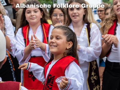 Man sieht eine Gruppe Jugendliche in Folklore Kleidung in einer Gruppe tanzen.