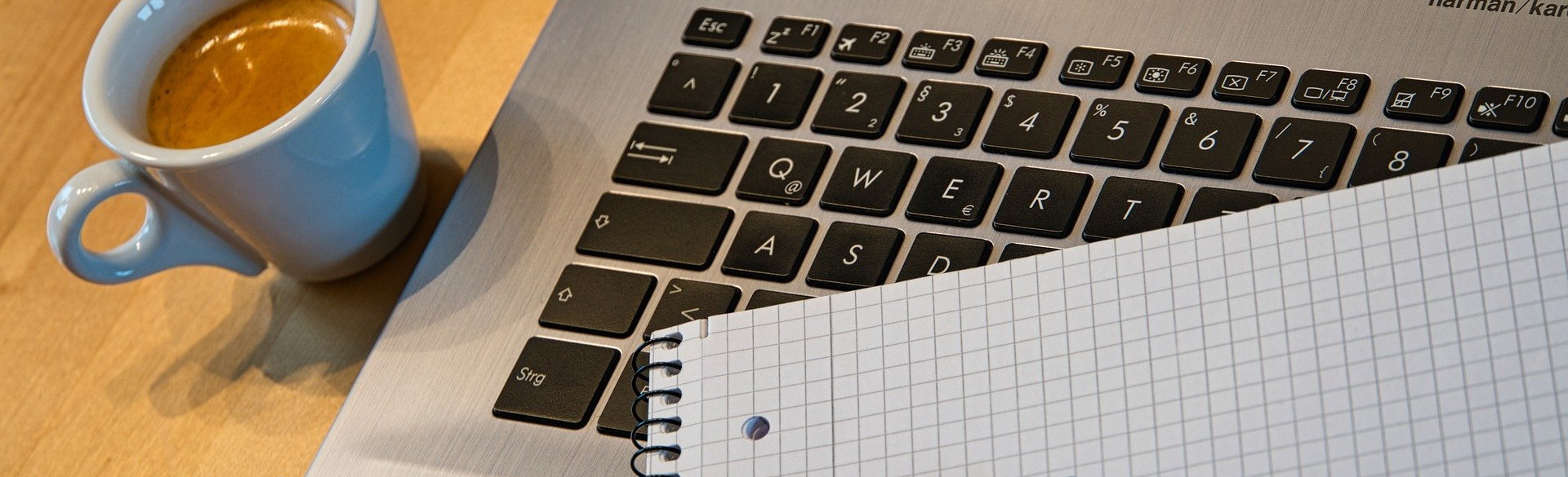 Laptop mit Kaffeetasse und Block